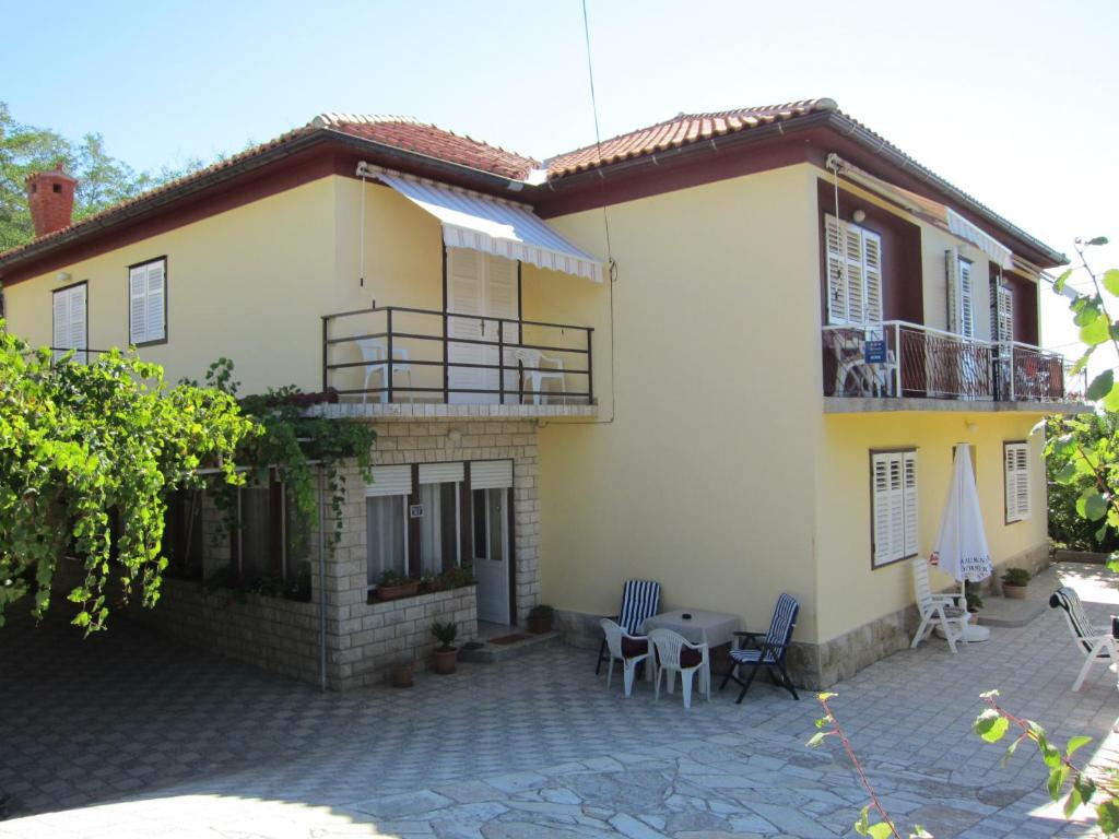 a large house with a patio and a balcony at Apartments & Rooms Sanja in Rab