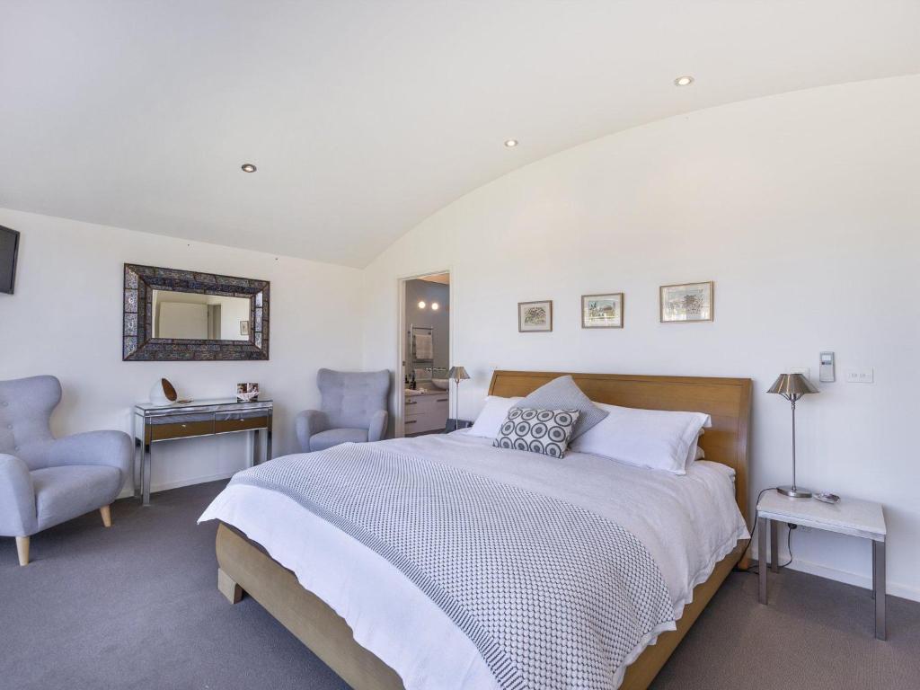 a bedroom with a bed and two chairs and a mirror at The Quarterdeck in Port Fairy