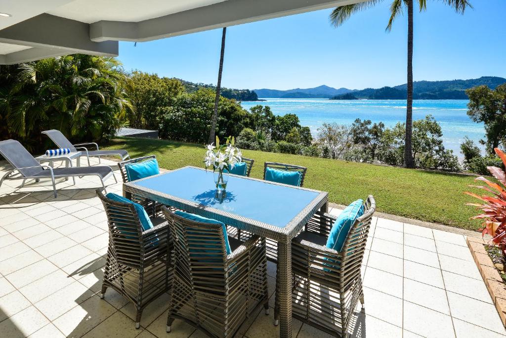 een tafel en stoelen op een patio met uitzicht op het water bij Hamilton Island Holiday Homes in Hamilton Island