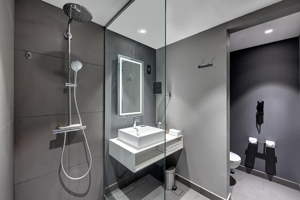 a bathroom with a sink and a shower and a mirror at Novotel Sharjah Expo Centre in Sharjah