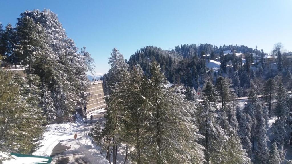 a snow covered mountain with trees and a building at Shangrila Hotels & Resorts Changla Gali in Abbottabad