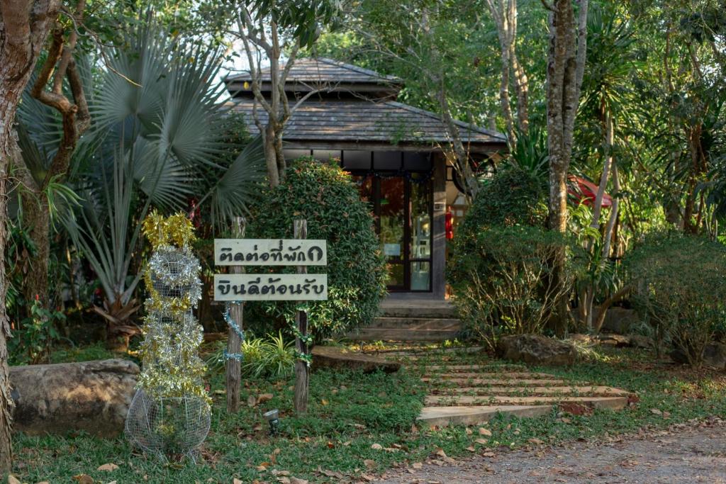 a sign in front of a house with a building at Baan Suan Ramita Resort in Chanthaburi