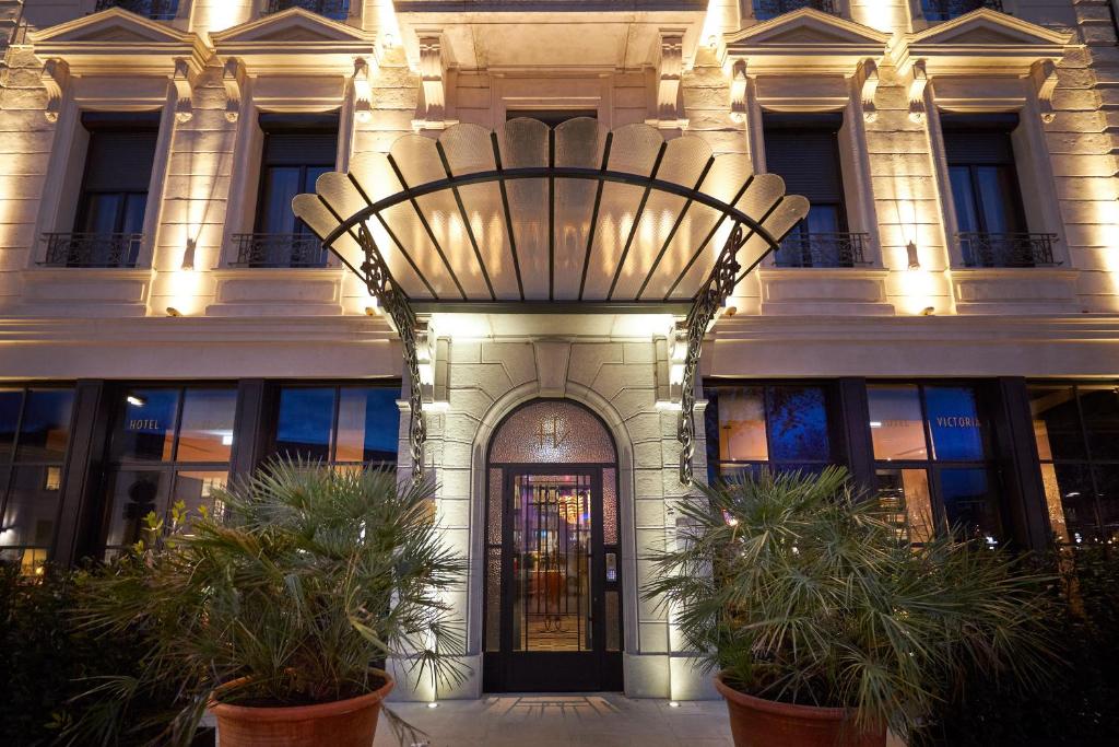 un grand bâtiment avec une porte et des plantes devant lui dans l'établissement Hotel Victoria, à Valence