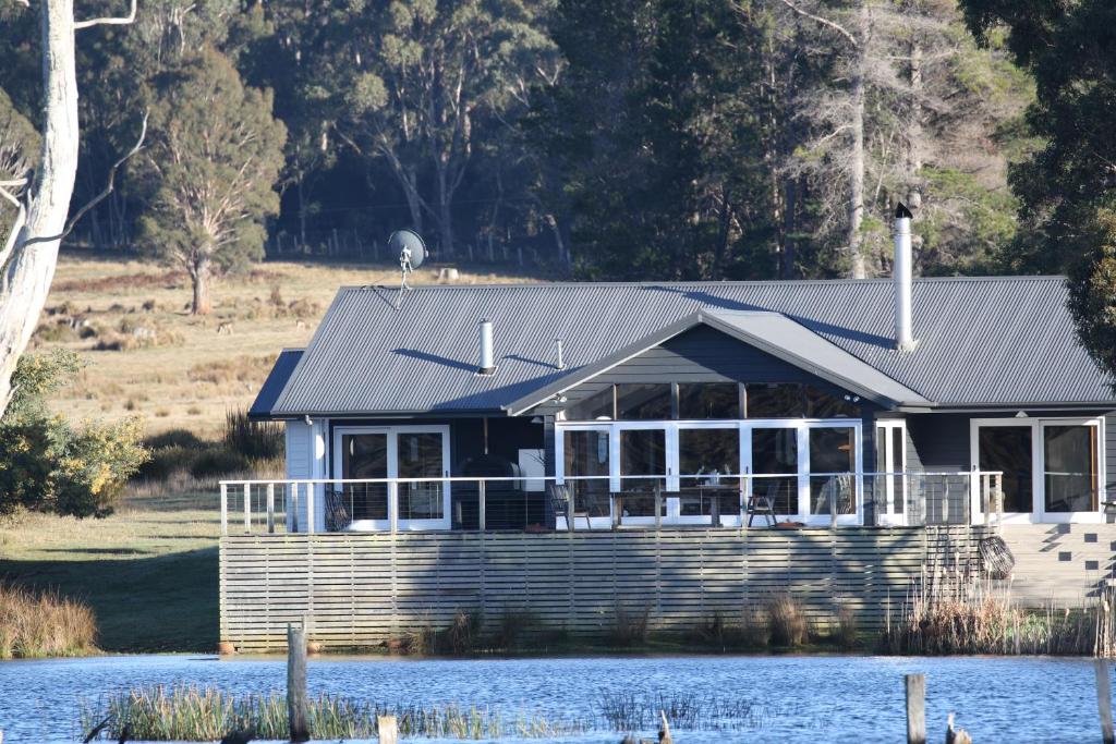 Currawong Lakes Tasmania في Lake Leake: منزل على الماء مع منزل في الأعلى