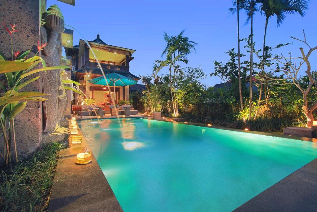 a swimming pool in front of a house at D'Legon Luxury Villas in Ubud