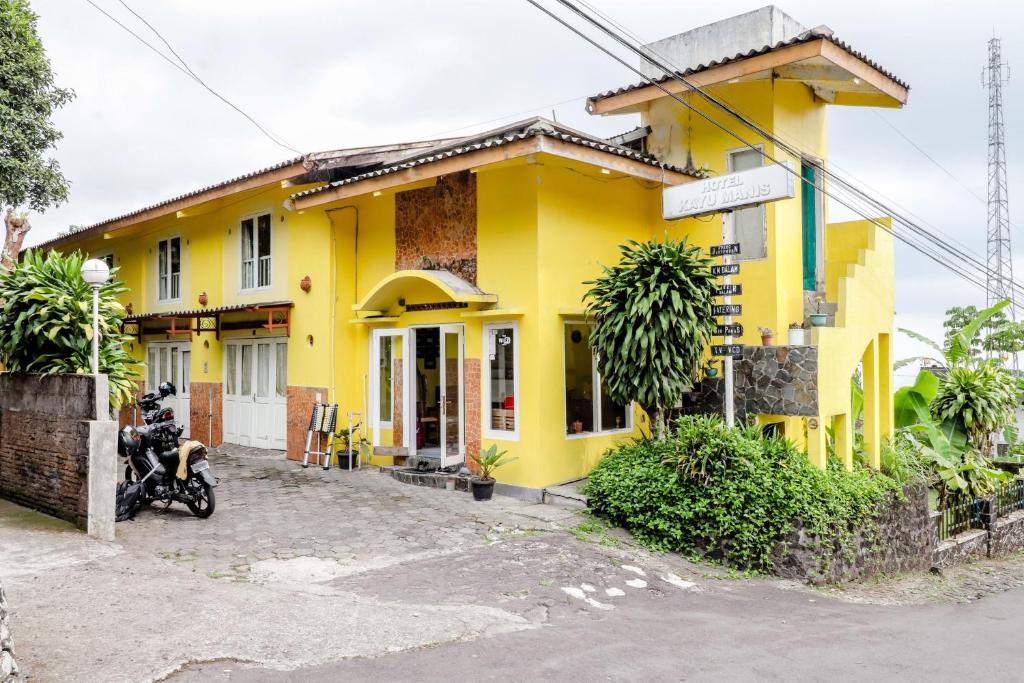 una casa amarilla con una motocicleta estacionada frente a ella en Hotel Kayu Manis en Kaliurang