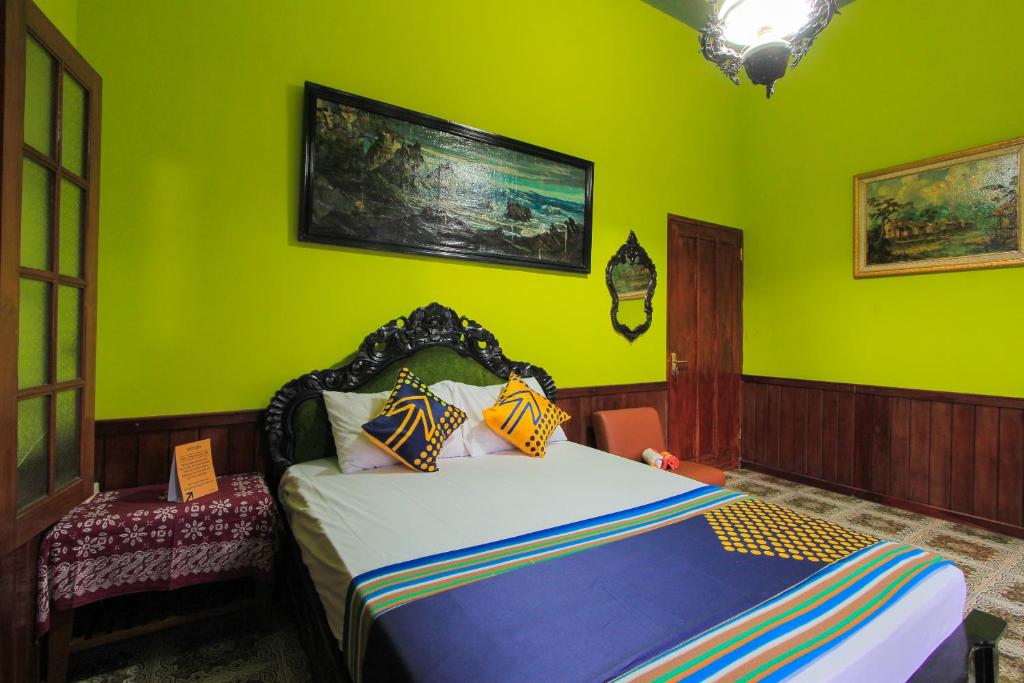una camera da letto con pareti verdi e un letto con cuscini colorati di SPOT ON 2490 Griya Kencana Homestay a Banyuwangi