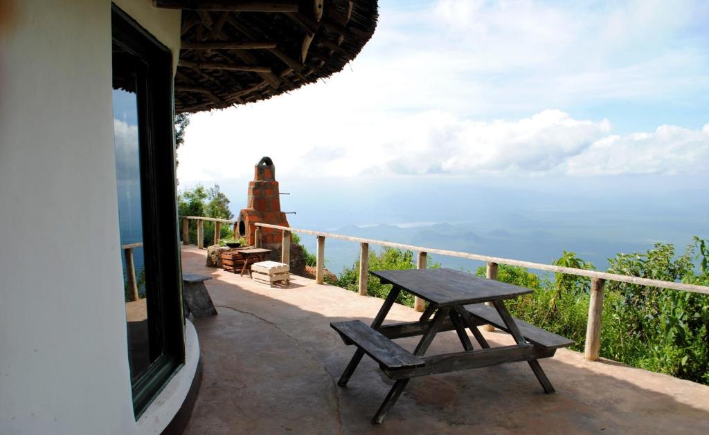 una mesa y un banco en un balcón con vistas al océano en Mambo View Point, en Ndungu