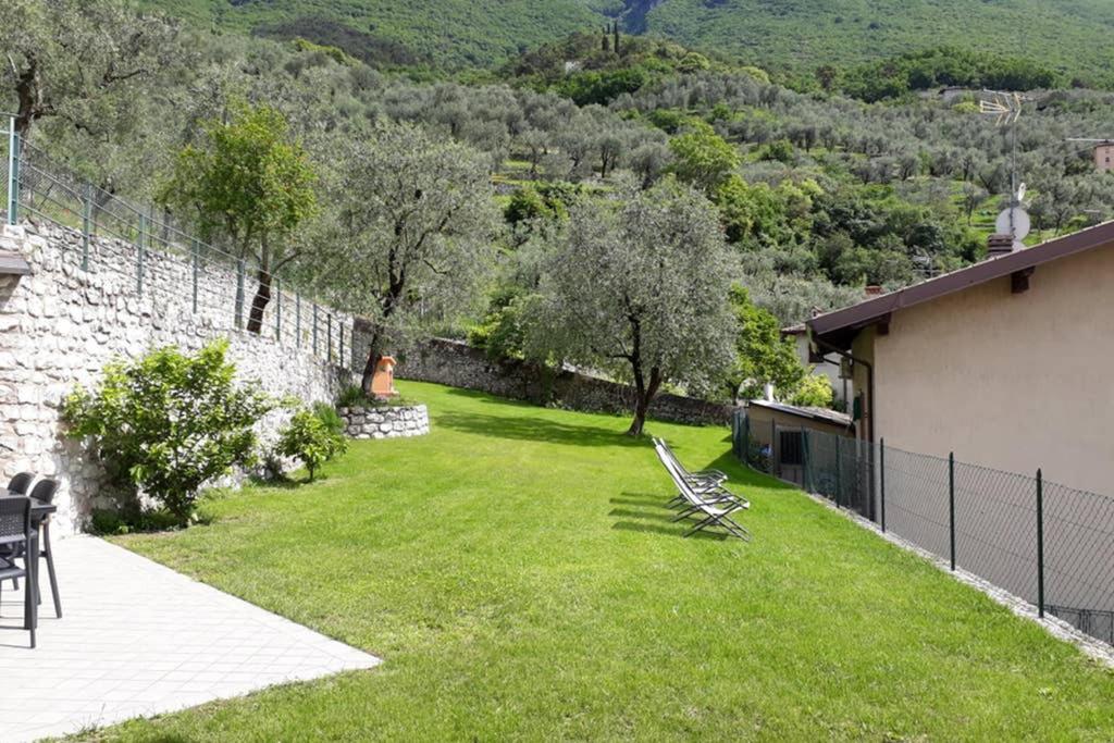a yard with a stone wall and chairs in the grass at Casa/Villa Sommavilla in Brenzone sul Garda