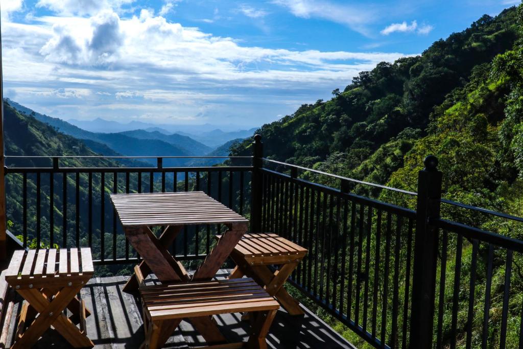 a wooden table and chairs on a balcony with mountains at Ella Camelot in Ella