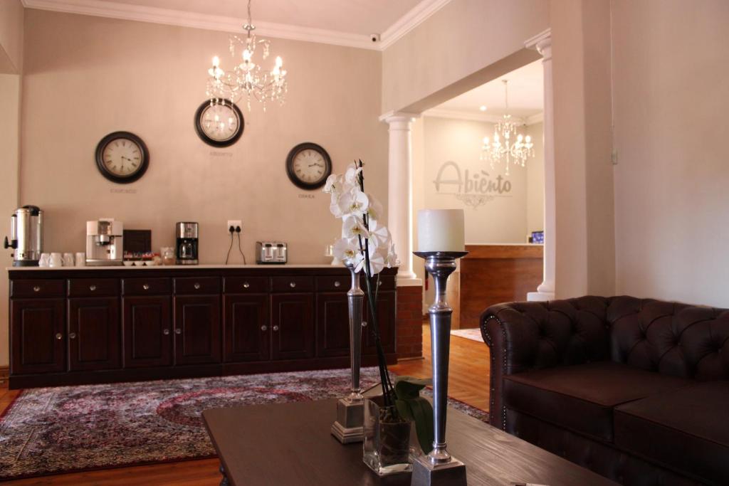 a living room with a couch and clocks on the wall at Abiento Guesthouse in Bloemfontein