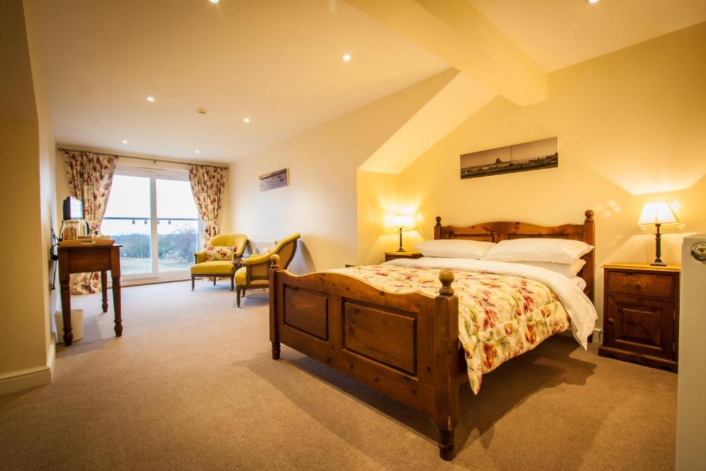 a bedroom with a large bed and a desk at Dene House Farm in Longframlington