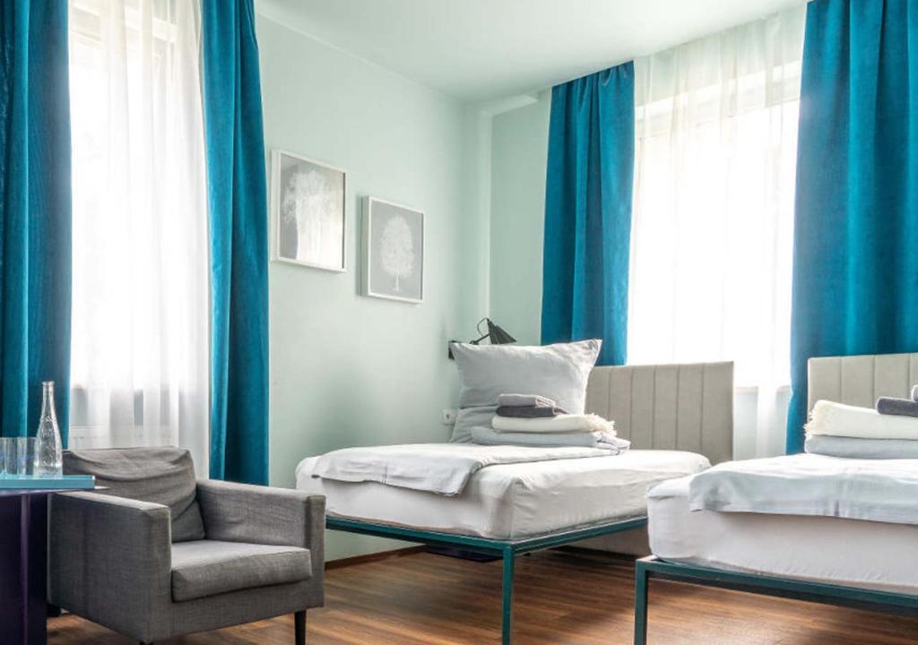 a bedroom with blue curtains and a bed and a chair at Das Schreder Hotel in Munich