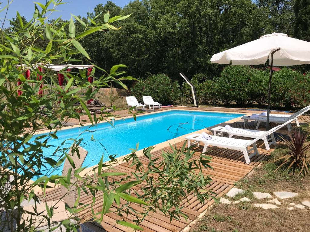 a swimming pool with an umbrella and two lounge chairs next to it at Mas du tilleul in Callian