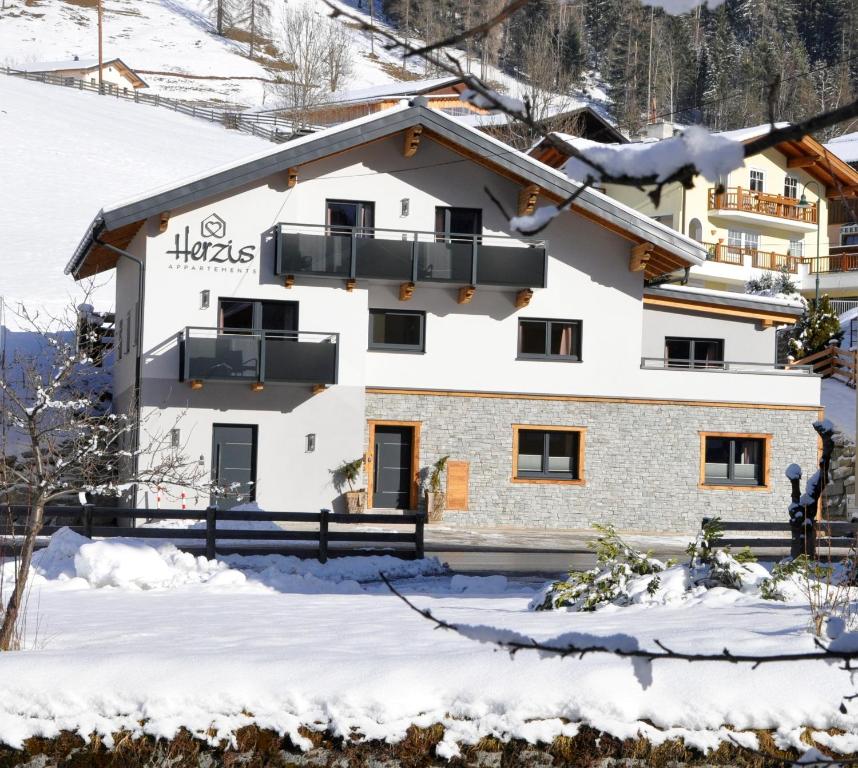une maison dans la neige dans les montagnes dans l'établissement Herzis Appartements, à Wagrain