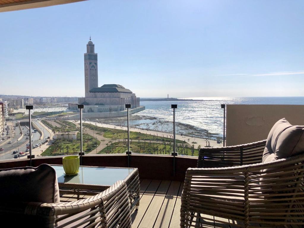 einen Balkon mit Blick auf das Meer und einen Uhrturm in der Unterkunft KEEP CALM AND THINK OF THE SEA, MARINA!! in Casablanca