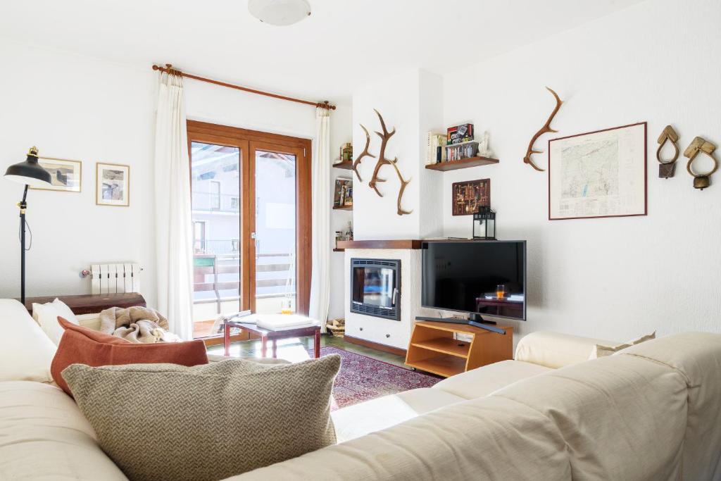 a living room with a white couch and a tv at Orobie Aprica Apartment in Aprica