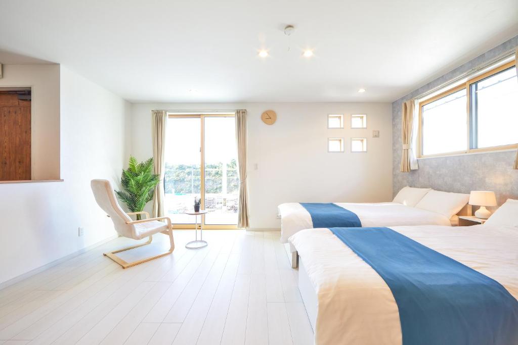ein Schlafzimmer mit 2 Betten und einem Stuhl darin in der Unterkunft E-horizon Resort コンドミニアム名護 C in Nago