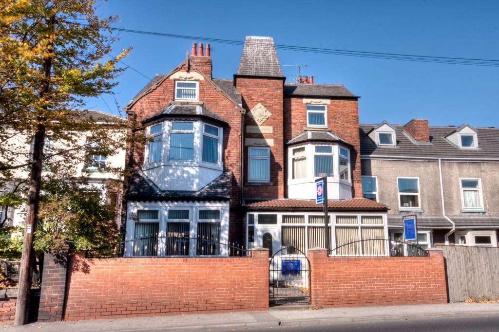 a large house with a brick fence in front of it at Tower House Executive Guest House in Pontefract