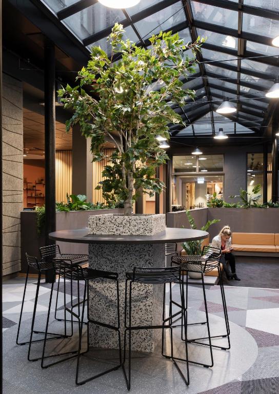 a woman sitting at a table with a tree at Citybox Oslo in Oslo
