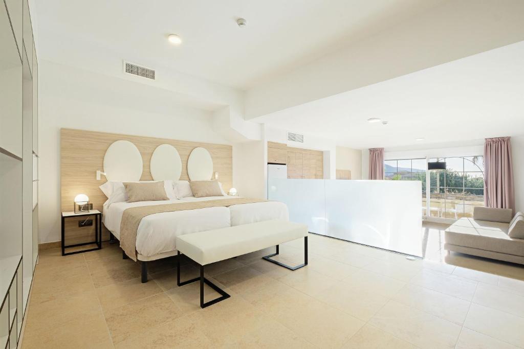 - une chambre blanche avec un lit et un canapé dans l'établissement Envía Almería Apartments Spa & Golf, à Aguadulce