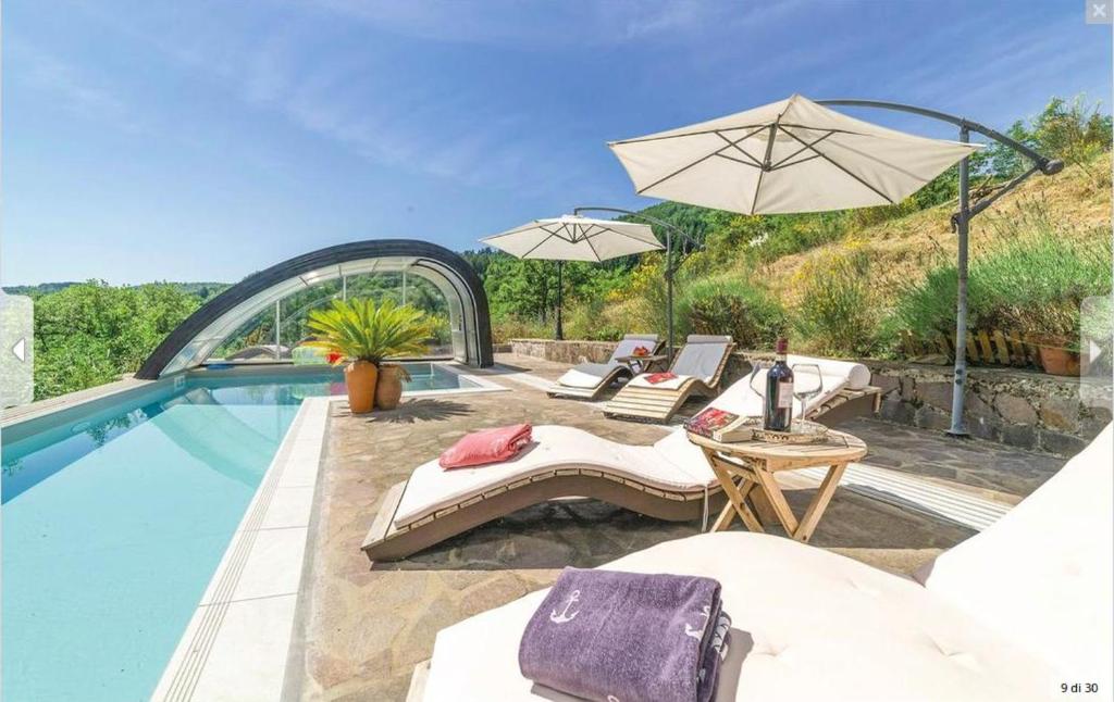 a swimming pool with two chairs and an umbrella at DeiMori LaMassa private villa with pool in Castel San Niccolò