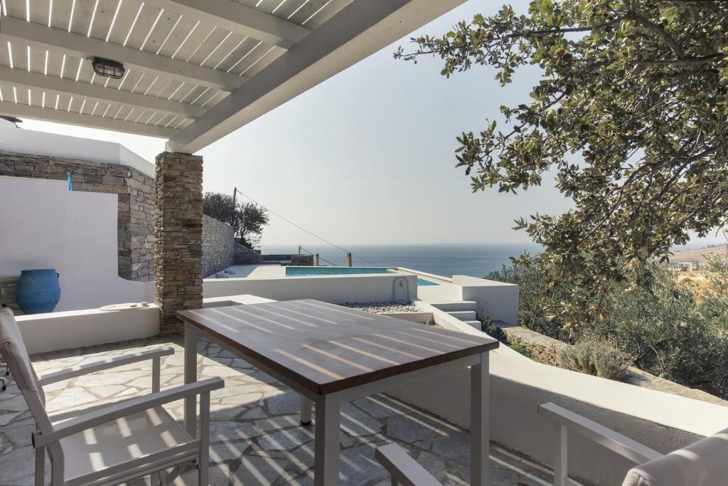 una mesa y sillas en un patio con vistas al océano en Apartment with a sea view and swimming pool, in the area of Koundouros, en Koundouros