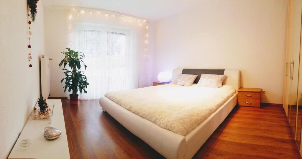 a bedroom with a large white bed and a plant at Bismarck Apartment in Pirmasens