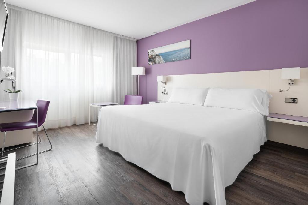 Pokój hotelowy z dużym białym łóżkiem i biurkiem w obiekcie Exe Coruña w mieście A Coruña