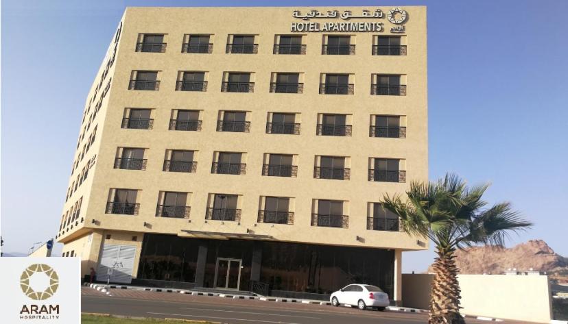 um edifício com uma palmeira em frente em Tanuma Aram Hospitality - Hotel Apartments em Tanomah