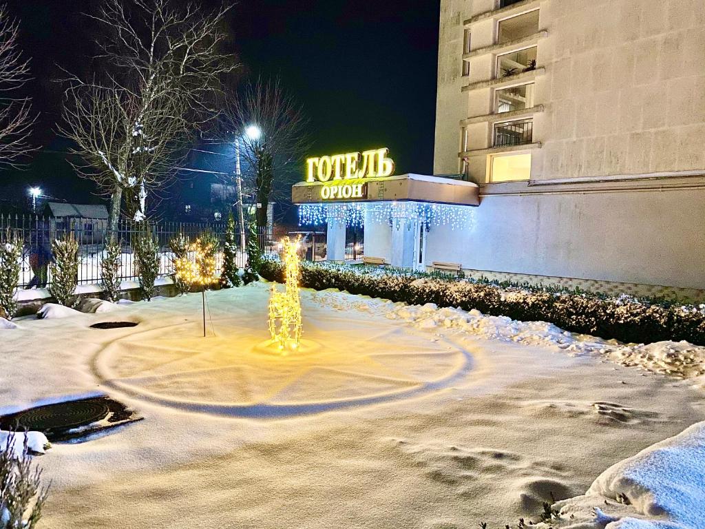 un edificio con un letrero iluminado en la nieve en Hotel Orion, en Morshyn