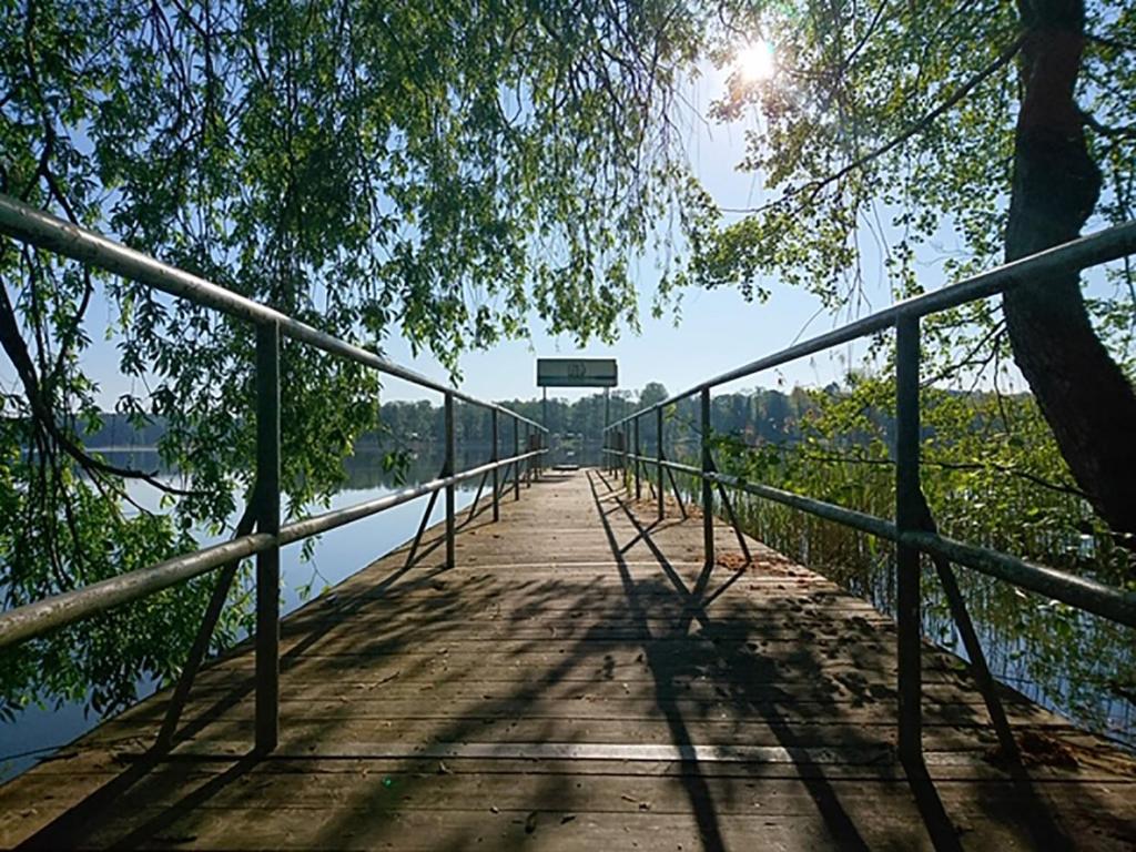 a bridge over a body of water with the sun shining at Waldschenke Stendenitz Übernachten im Wald am See in Neuruppin