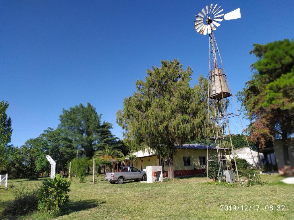 un molino de viento frente a una casa con un camión en La Sampedrita en San Pedro