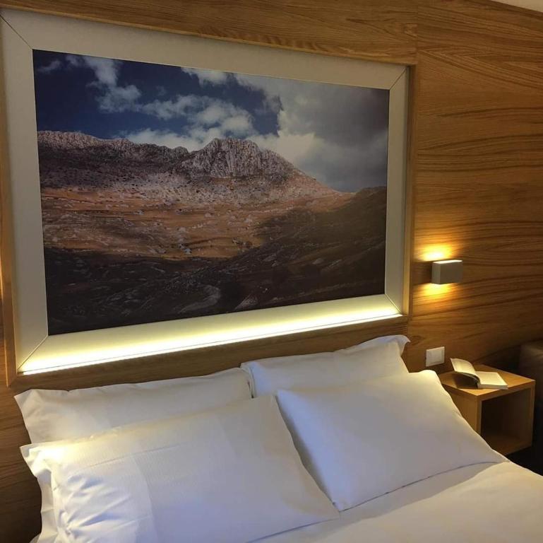 una camera da letto con un dipinto sopra un letto con cuscini bianchi di Hotel Miramonti a Castel del Monte
