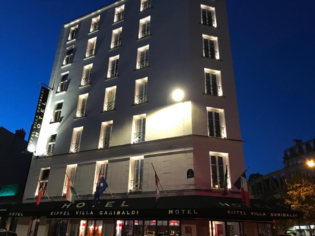 Un grand bâtiment blanc avec des drapeaux. dans l'établissement Eiffel Villa Garibaldi, à Paris