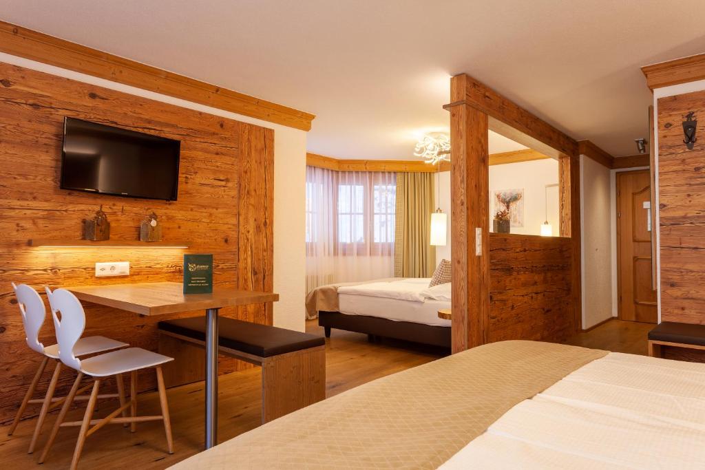 ein Schlafzimmer mit einem Bett und einem Schreibtisch mit einem Fernseher in der Unterkunft Hotel Jägerhof in Zermatt
