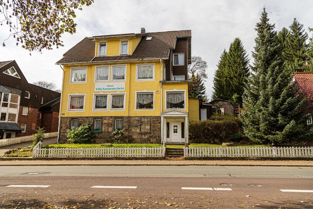 una casa amarilla al lado de una calle en Ski und Biker Hotel Villa Sonnenschein Braunlage am Wurmberg en Braunlage