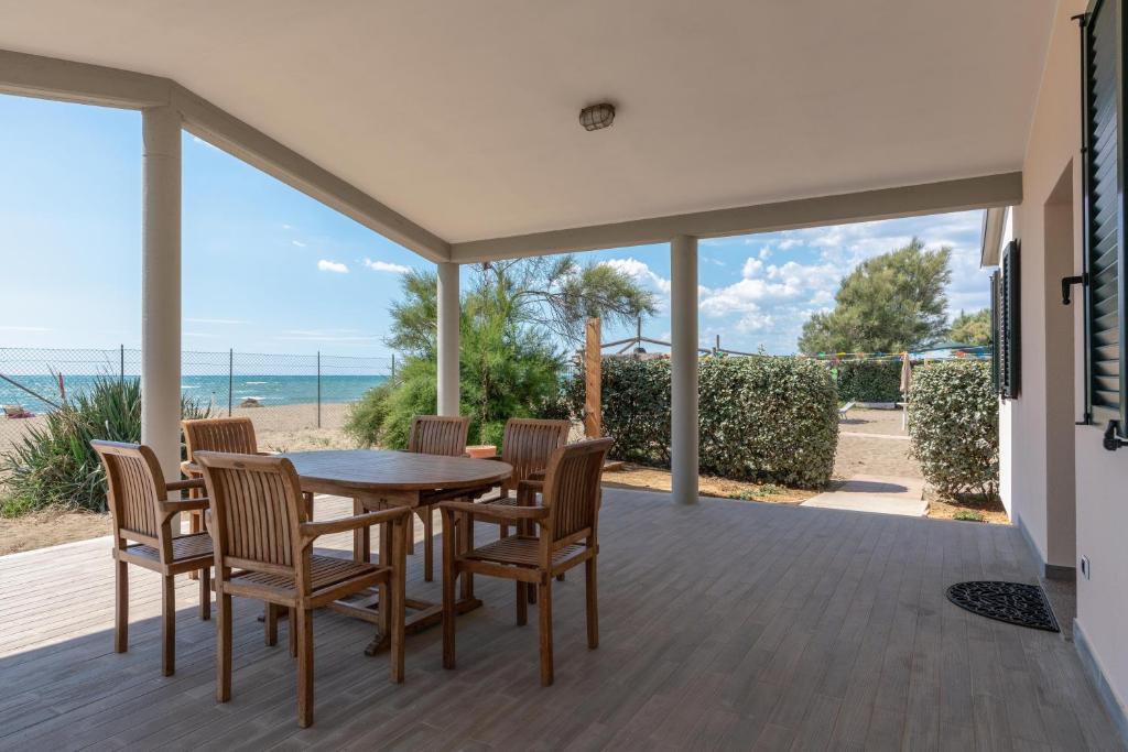 um pátio com uma mesa e cadeiras e a praia em Villa Alessandri - Direttamente sulla Spiaggia em Albinia