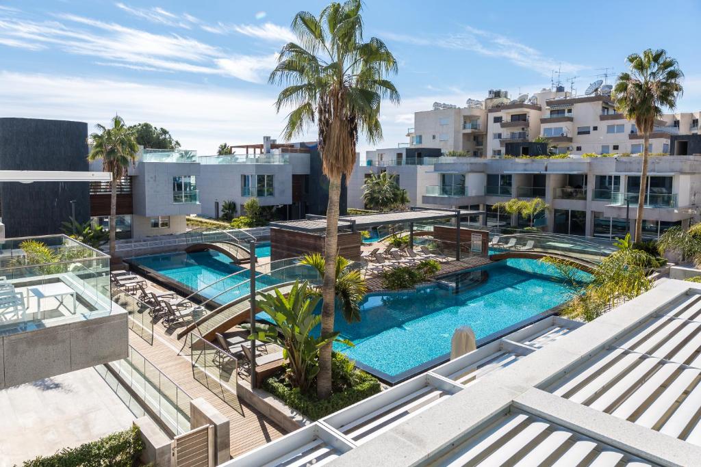 uma vista aérea de uma piscina com palmeiras e edifícios em Carmencita Studio B14 with pool & gym em Limassol