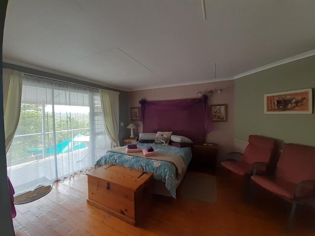a bedroom with a bed and a large window at De' Nessie in Port Alfred