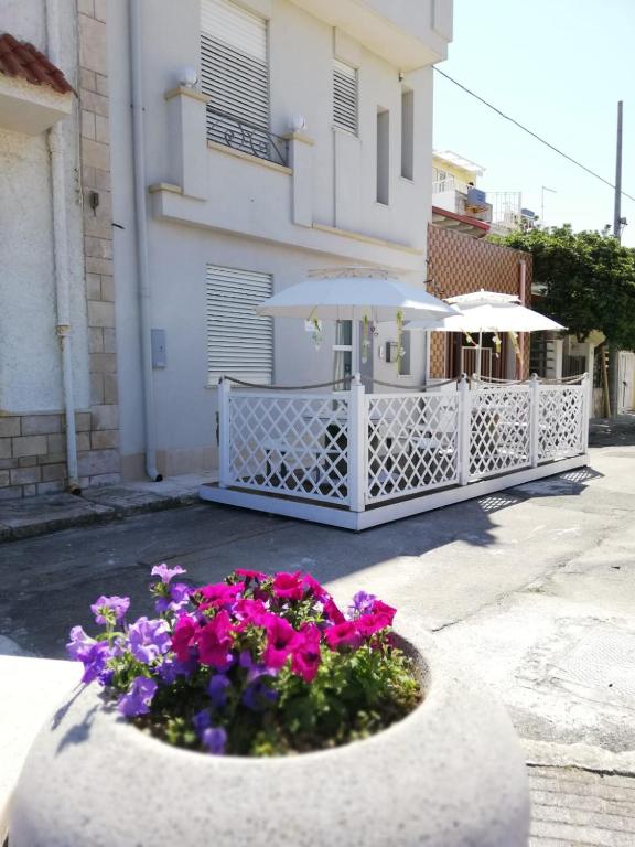 a planter with flowers and an umbrella in front of a building at Dimore di Mare in San Pietro Vernotico