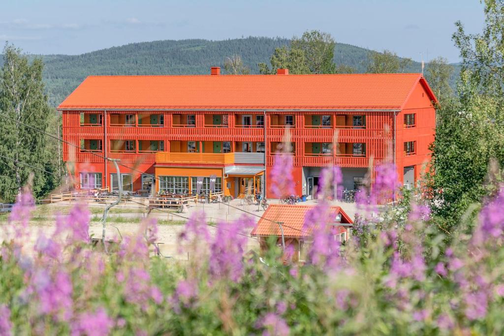 ein Gebäude mit einem orangenen Dach und lila Blumen in der Unterkunft JBP Hotell in Järvsö