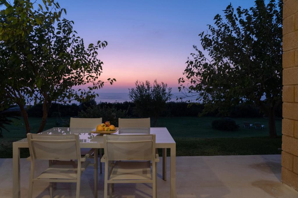 a table with chairs and a bowl of fruit on it at Sunset Villas in Falasarna