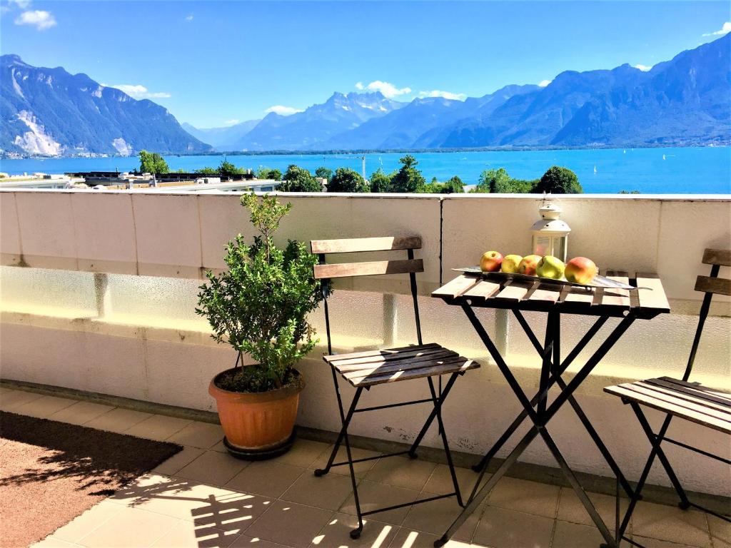 einen Balkon mit 2 Stühlen und einem Tisch mit Obst darauf in der Unterkunft Central Studio with Lake View | 102 in Montreux