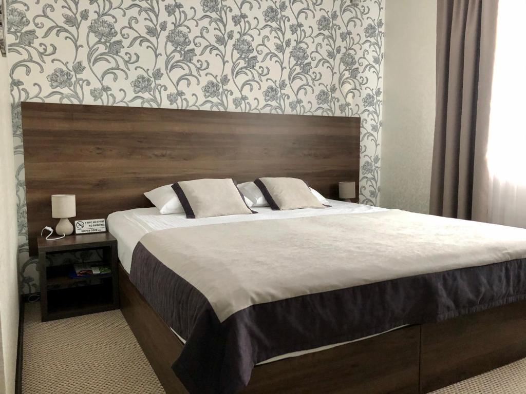 オムスクにあるAvenue Hotelのベッドルーム1室(大型ベッド1台、木製ヘッドボード付)