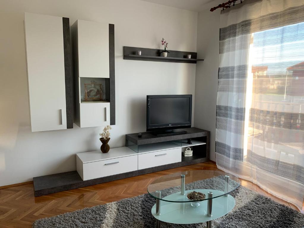 ein Wohnzimmer mit einem TV und einem Glastisch in der Unterkunft Apartman MADAPE in Sesvete