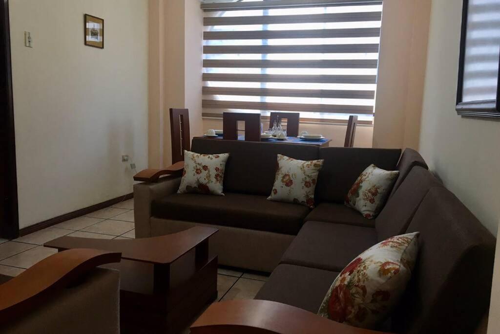 uma sala de estar com um sofá castanho e uma janela em Confortable mini departamento em Loja