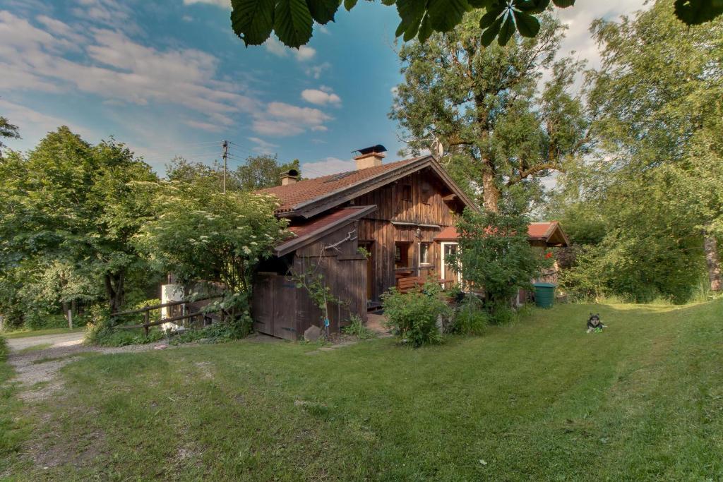 una casa de madera con un perro delante en Ferienwohnung Schmidt - Natur und Ruhe, en Schwaigen