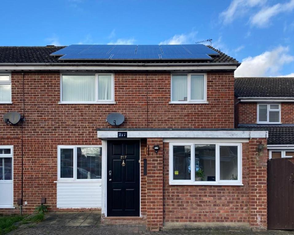 une maison en briques rouges avec des panneaux solaires sur le toit dans l'établissement Lovely Homes, à Aylesbury