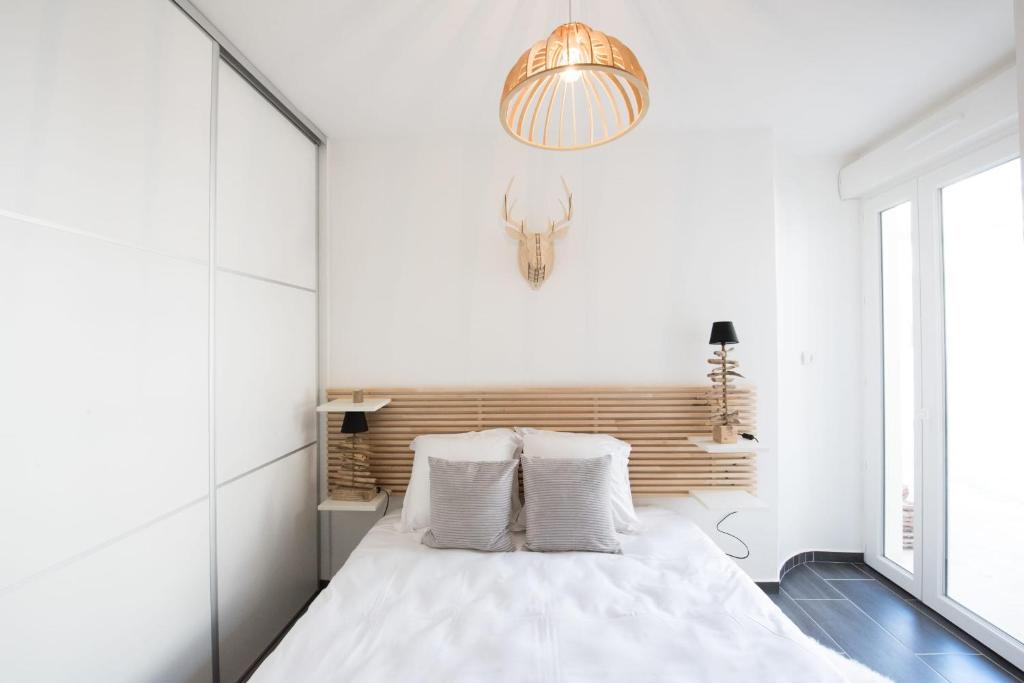 um quarto branco com uma cama e um lustre em Le Hirvi - cocon zen et épuré à 10min Vieux Lyon em Lyon